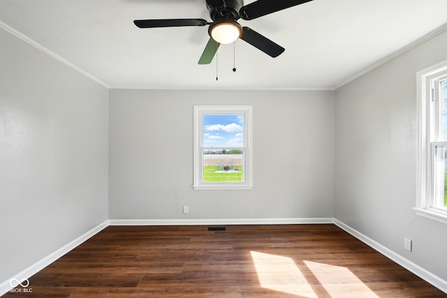 spare room featuring healthy amount of natural light, crown molding, baseboards, dark wood-type flooring, and a ceiling fan