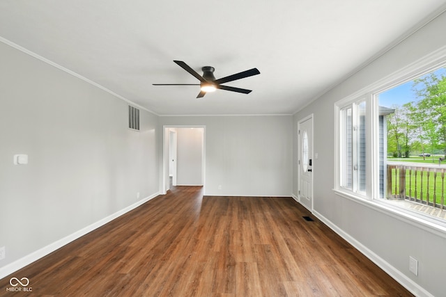 empty room featuring wood finished floors, crown molding, ceiling fan, and baseboards