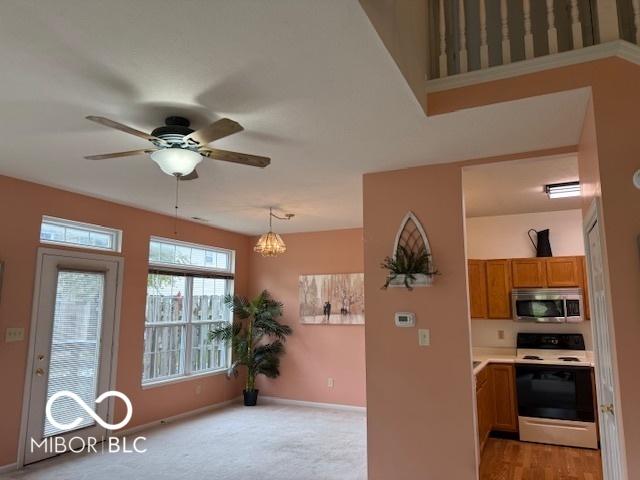 8002 Windham Lake Way Unit 33, Indianapolis, IN 46214 - kitchen with electric range, stainless steel microwave, brown cabinetry, ceiling fan, and baseboards