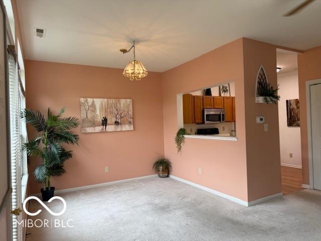 8002 Windham Lake Way Unit 33, Indianapolis, IN 46214 - unfurnished dining area featuring light carpet, a chandelier, and baseboards