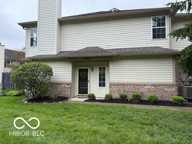8002 Windham Lake Way Unit 33, Indianapolis, IN 46214 - rear view of house featuring brick siding, a lawn, a chimney, and central AC