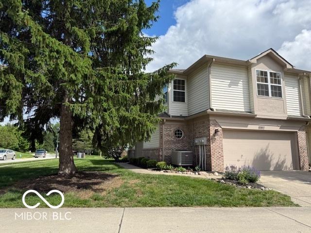 8002 Windham Lake Way Unit 33, Indianapolis, IN 46214 - view of side of home featuring brick siding, an attached garage, cooling unit, and a yard