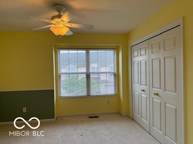 8002 Windham Lake Way Unit 33, Indianapolis, IN 46214 - unfurnished bedroom with light carpet, baseboards, a closet, and a ceiling fan