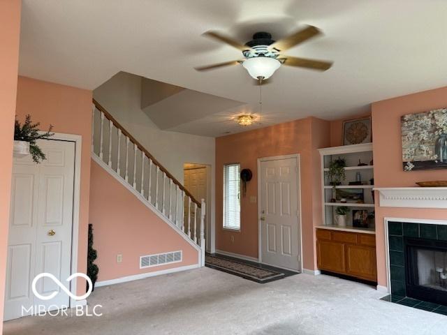 8002 Windham Lake Way Unit 33, Indianapolis, IN 46214 - carpeted entrance foyer featuring stairway, a tiled fireplace, ceiling fan, and baseboards