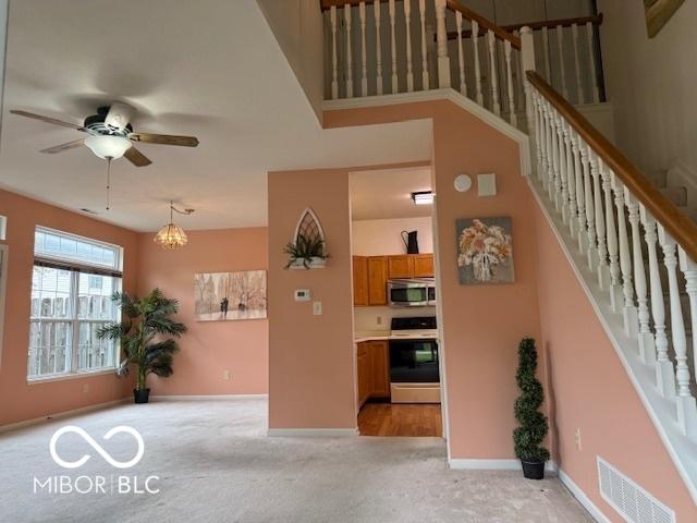 8002 Windham Lake Way Unit 33, Indianapolis, IN 46214 - living room with stairs, light colored carpet, ceiling fan, baseboards, and a chandelier