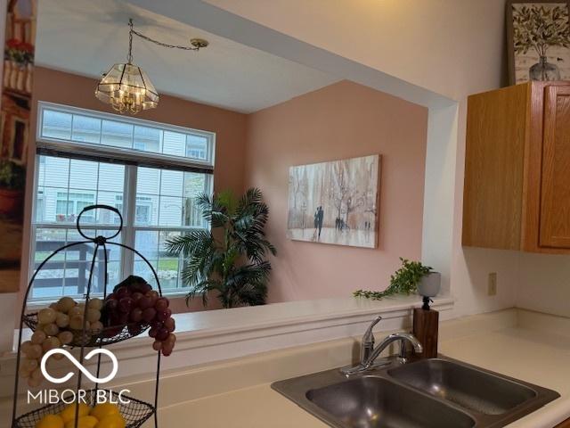 8002 Windham Lake Way Unit 33, Indianapolis, IN 46214 - kitchen featuring a sink, a chandelier, light countertops, pendant lighting, and brown cabinets