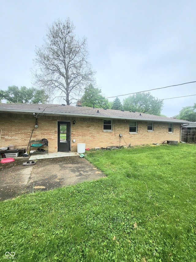 7109 Chandler Dr, Indianapolis, IN 46217 - back of property featuring a patio, brick siding, and a lawn
