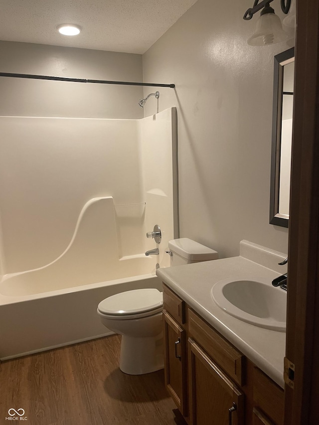 8234 Crosser Dr, Indianapolis, IN 46237 - bathroom with a textured ceiling, toilet, vanity, shower / washtub combination, and wood finished floors