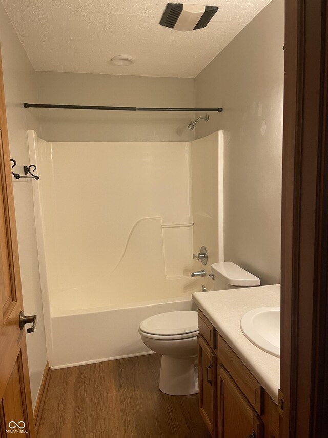 8234 Crosser Dr, Indianapolis, IN 46237 - bathroom with shower / bathtub combination, a textured ceiling, toilet, vanity, and wood finished floors