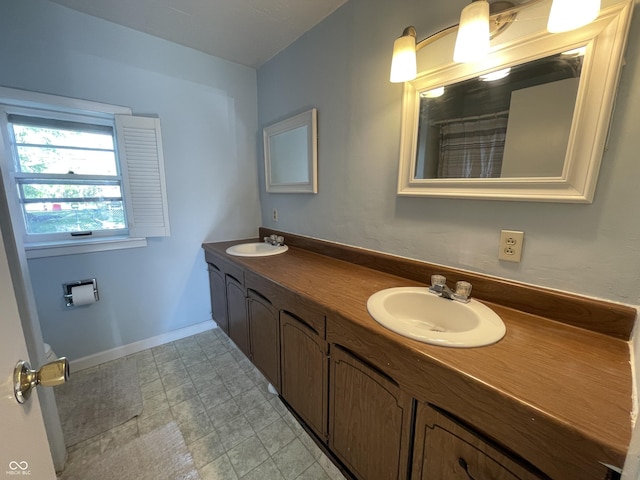 full bath featuring baseboards, double vanity, and a sink