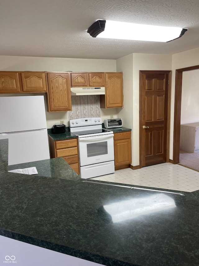 kitchen with white appliances, under cabinet range hood, dark countertops, and light floors