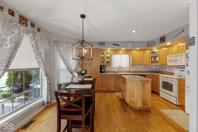 kitchen with white appliances, a center island, light countertops, and healthy amount of natural light