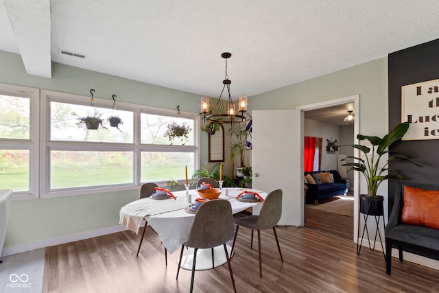 dining room featuring wood finished floors, a chandelier, baseboards, and a textured ceiling