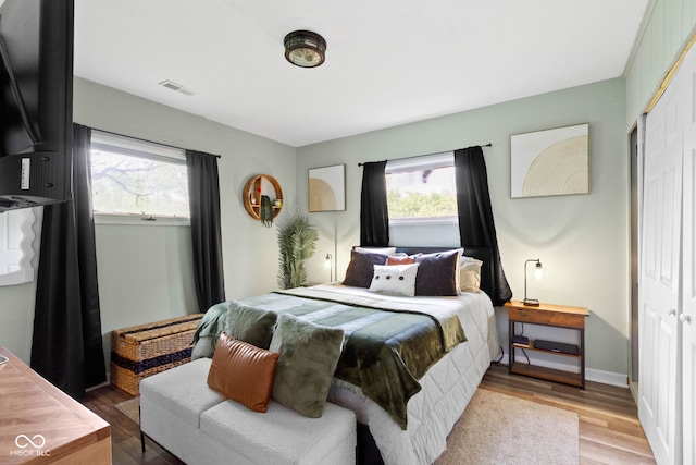 bedroom with wood finished floors, a closet, and baseboards