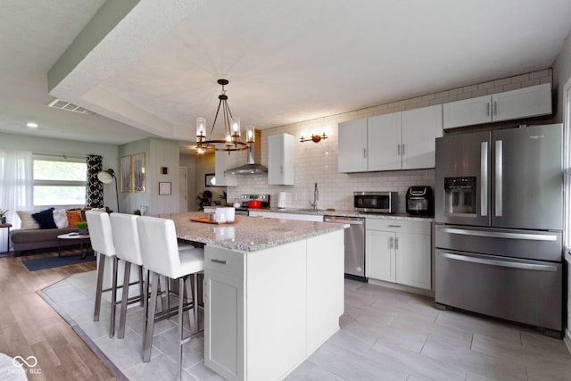 kitchen with appliances with stainless steel finishes, a chandelier, a sink, a center island, and backsplash