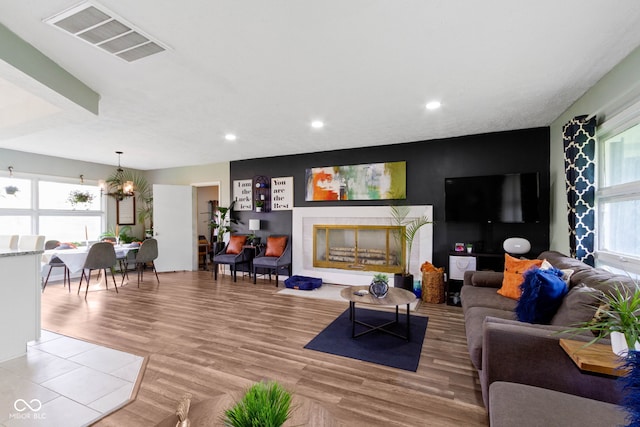 living room with recessed lighting, a chandelier, a fireplace, and light wood-type flooring