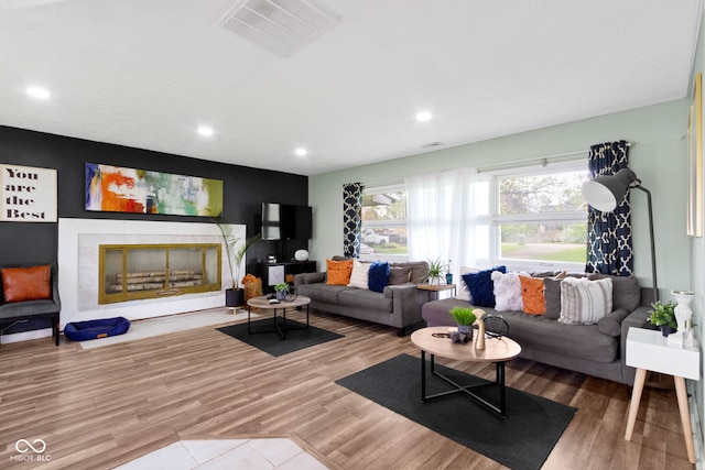 living room featuring recessed lighting, wood finished floors, and a tile fireplace