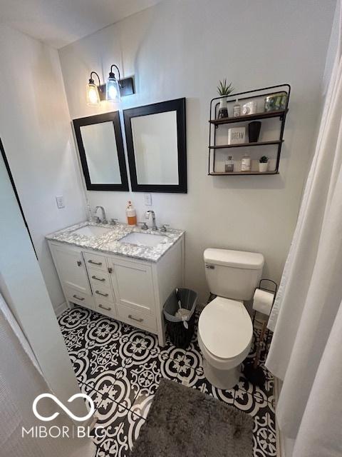full bath featuring toilet, double vanity, and tile patterned floors