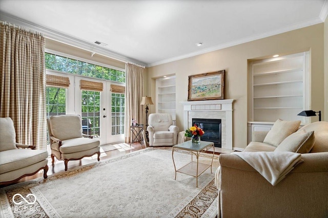 living area with ornamental molding, built in shelves, a high end fireplace, french doors, and light wood-style flooring