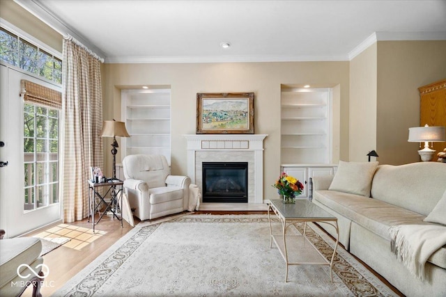 living room featuring crown molding, wood finished floors, a fireplace, and built in features