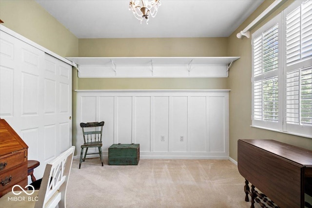 living area featuring light colored carpet, a chandelier, and baseboards