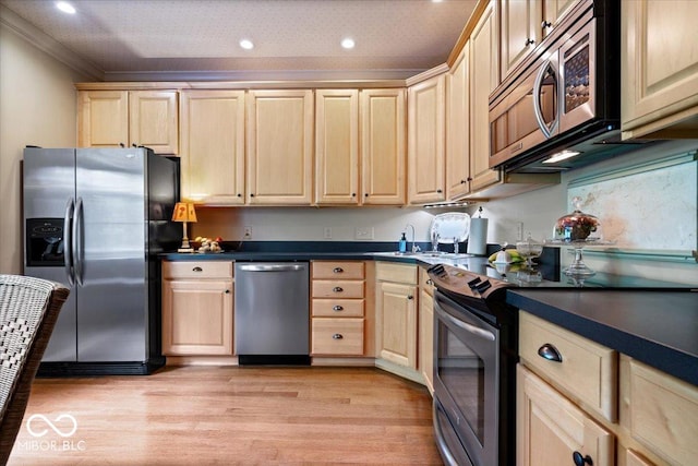 kitchen featuring stainless steel appliances, light brown cabinets, light wood finished floors, dark countertops, and recessed lighting