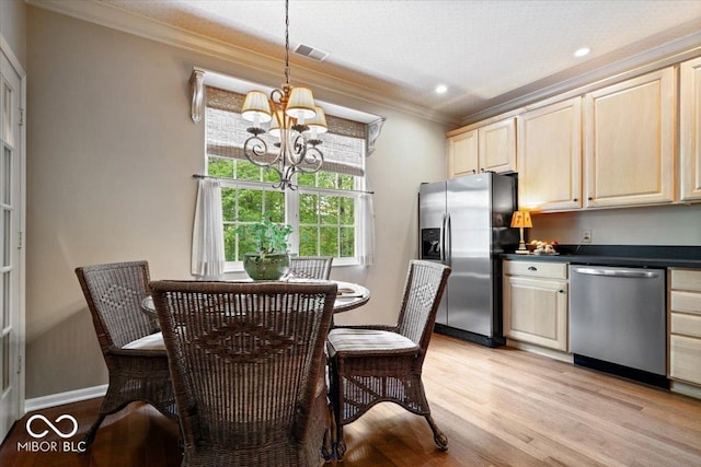 kitchen featuring appliances with stainless steel finishes, crown molding, a chandelier, light brown cabinetry, and dark countertops