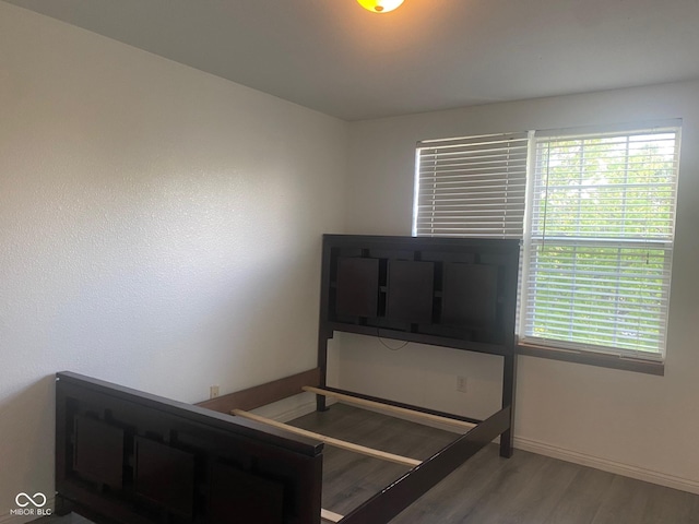 bedroom with wood finished floors, baseboards, and multiple windows