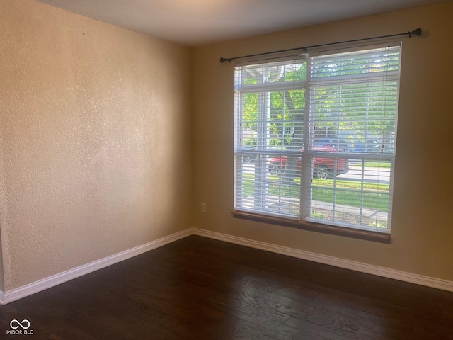 unfurnished room with baseboards and dark wood-style floors