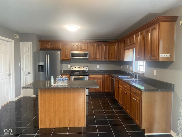 kitchen featuring a kitchen island, stainless steel appliances, a sink, and dark tile patterned floors