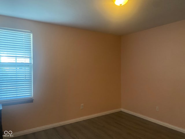 spare room with dark wood finished floors and baseboards