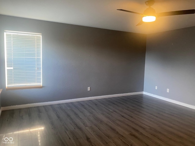 unfurnished room featuring baseboards, dark wood-type flooring, and a ceiling fan