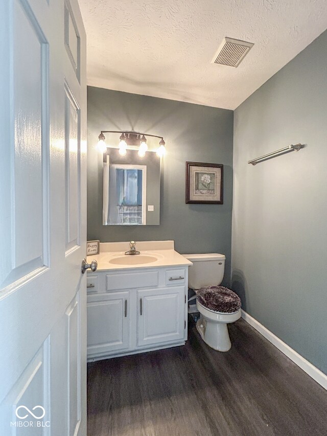 8798 Surrey Dr, Pendleton, IN 46064 - bathroom with wood finished floors, toilet, vanity, baseboards, and a textured ceiling
