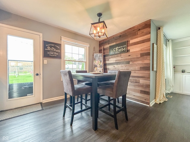 8798 Surrey Dr, Pendleton, IN 46064 - dining space featuring a chandelier, dark wood-style flooring, baseboards, and wood walls