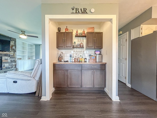 8798 Surrey Dr, Pendleton, IN 46064 - indoor dry bar featuring dark wood-type flooring, freestanding refrigerator, decorative backsplash, a ceiling fan, and baseboards