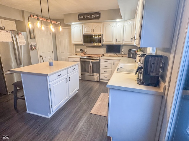 8798 Surrey Dr, Pendleton, IN 46064 - kitchen featuring appliances with stainless steel finishes, white cabinets, dark wood-style floors, light countertops, and a kitchen island