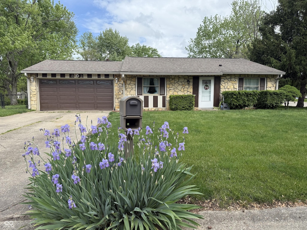 ranch-style home featuring stone siding, concrete driveway, an attached garage, and a front yard