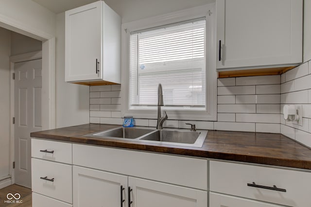 1517 Wallace Ave, Indianapolis, IN 46201 - kitchen with a sink, white cabinetry, wooden counters, and decorative backsplash
