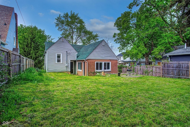 rear view of house with a yard, a fenced backyard, and brick siding