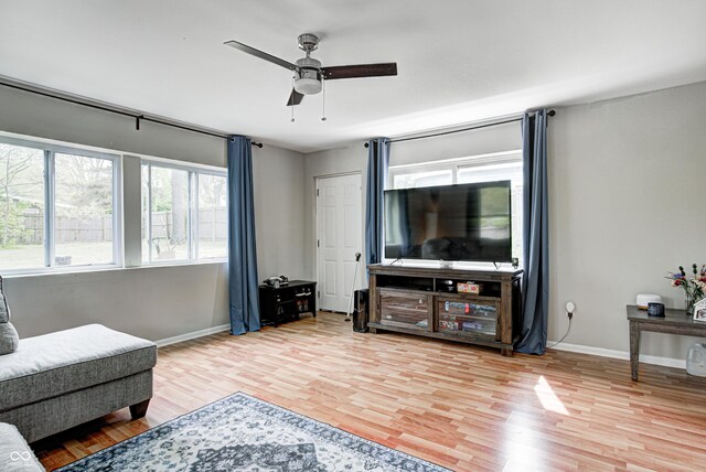 living room featuring wood finished floors, baseboards, and ceiling fan