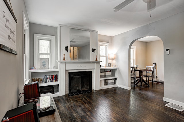 living area featuring ceiling fan, wood-type flooring, arched walkways, and visible vents