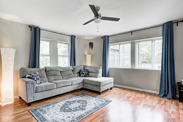 living room featuring baseboards, wood finished floors, and a ceiling fan