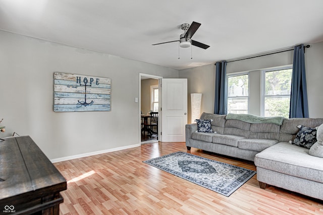 living area featuring baseboards, a ceiling fan, and wood finished floors