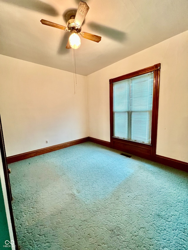 carpeted spare room with ceiling fan, baseboards, and visible vents