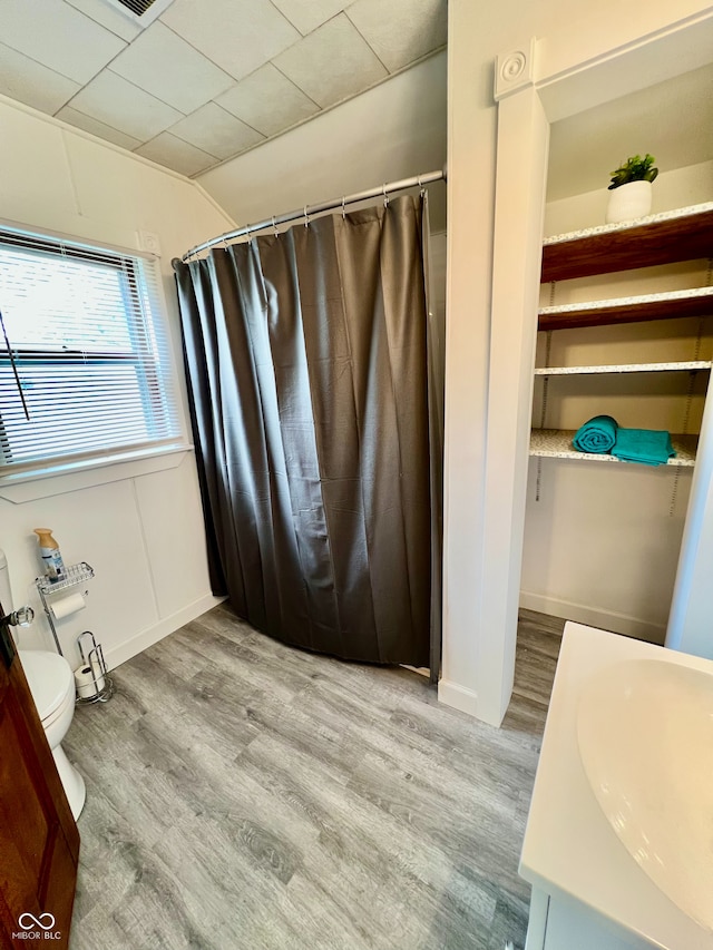 full bathroom with toilet, a shower with shower curtain, wood finished floors, and vanity