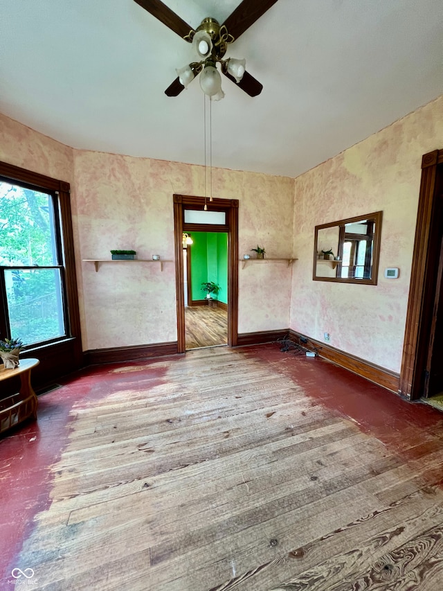 unfurnished living room with ceiling fan and baseboards