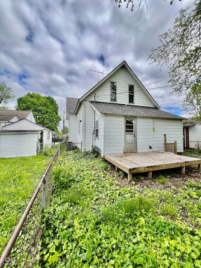 back of property with a shingled roof, fence, and a deck