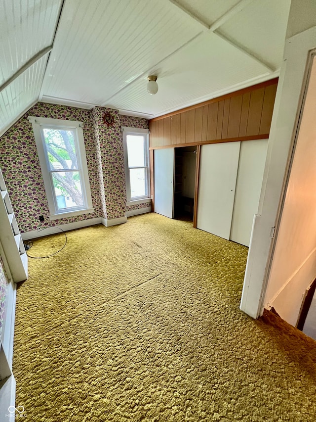 interior space with carpet flooring, wallpapered walls, and vaulted ceiling