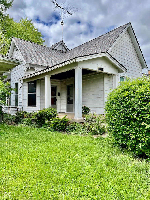 bungalow featuring a porch, roof with shingles, and a front lawn