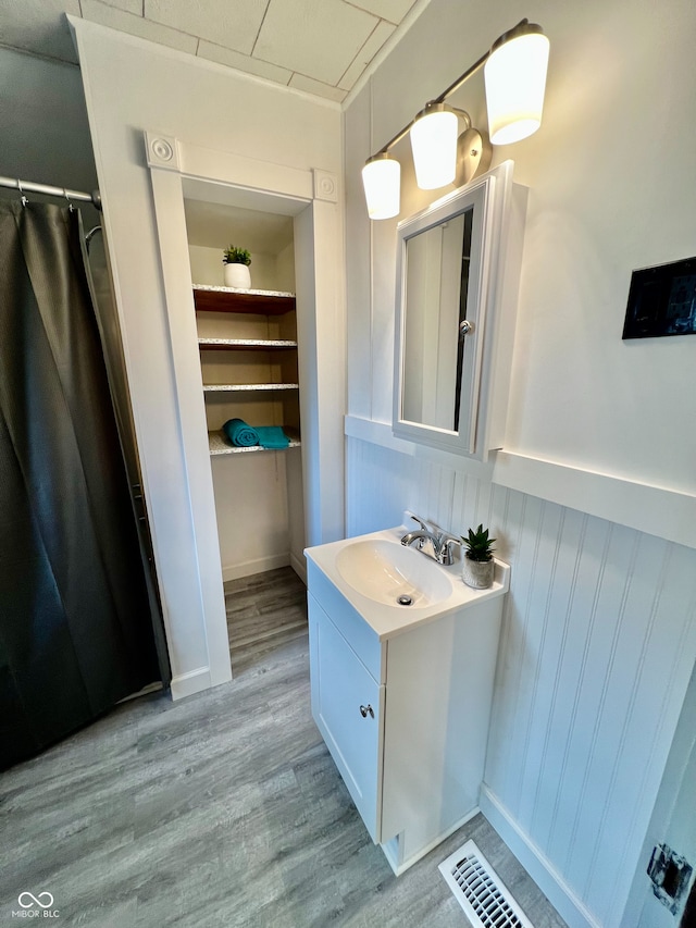 full bathroom featuring vanity, visible vents, and wood finished floors